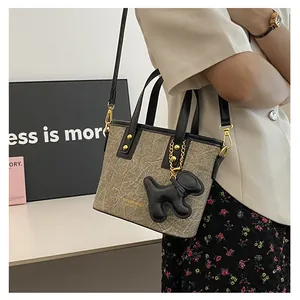 Nahaufnahme der grauen Marmor-Handtasche mit Welpen-Anhänger und goldener Ketten-Deko