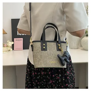 Detail der grauen Marmor-Tasche mit schwarzem Besatz, Gurt und Plüschtier-Anhänger