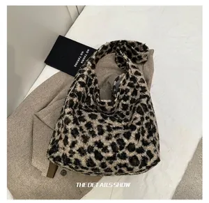 Detalle de bolso tote de punto leopardo sobre abrigo gris mostrando textura suave