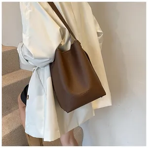 Detail of dark brown pebble leather bucket bag with slim shoulder strap and logo