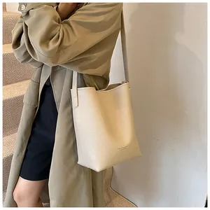 Detail view of cream bucket bag in lychee leather texture with fashion lettering