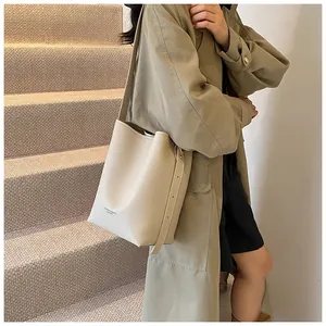 Detail of cream bucket bag featuring lychee texture and adjustable leather strap