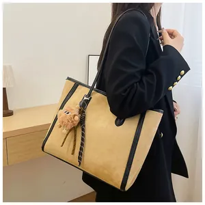 Detail of khaki suede tote bag with black leather trim and plush monster charm