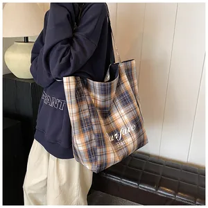 Detail of large yellow plaid tote bag with Our fave Party text shown on shoulder