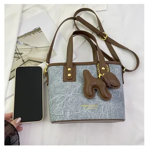 Mini-Bucket-Bag aus Denim mit braunem Lederbesatz und süßem Welpenanhänger auf Weiß