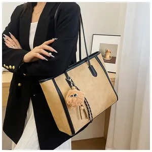 Detailed view of the khaki suede tote bag with black trim on a female model for style