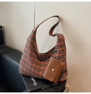 Close-up of houndstooth hobo bag with leather strap and a mini square pouch