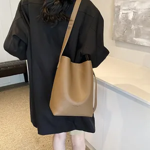 Brown litchi grain bucket bag set worn by model in a minimalist indoor setting