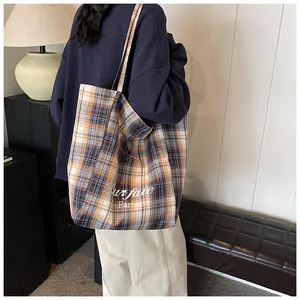 Rear view of a model carrying a large plaid tote bag with orange and blue check patterns