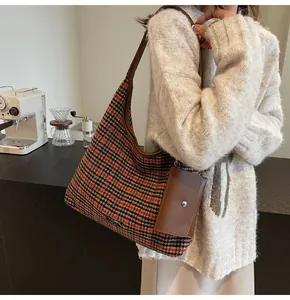Detail of houndstooth shoulder bag with brown leather trim and mini pouch on strap