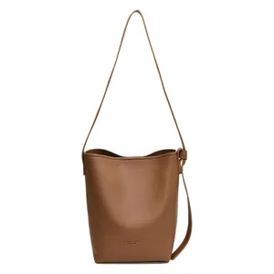 Brown litchi texture leather bucket bag with slim shoulder strap on white background