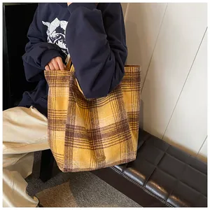 Detail of yellow plaid wool tote bag showing handmade metal plaque and thick texture