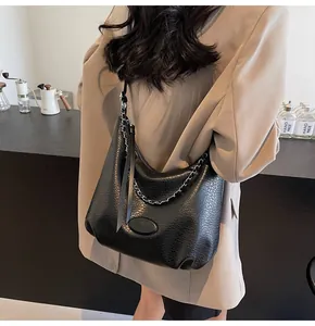 Dettaglio borsa tote in pelle martellata nera con catena e nappa decorativa
