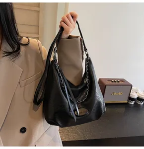 Dettaglio della borsa Hobo in pelle martellata nera con catena metallica e nappa in pelle