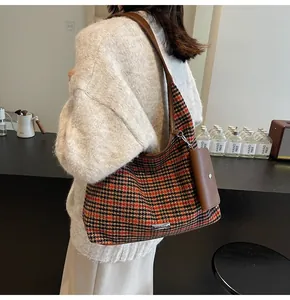Detail of houndstooth shoulder bag with brown leather strap and mini pouch accessory