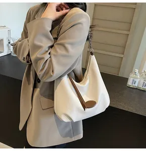Vista laterale della borsa tote minimalista in pelle bianco crema con tracolla a catena