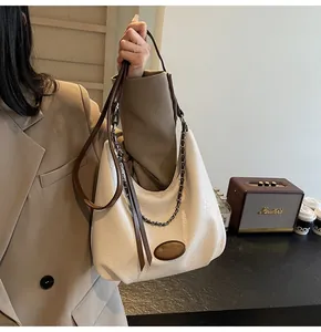 Dettaglio borsa hobo in pelle bianca con tracolla marrone e catena decorativa d'argento