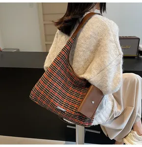 Close-up of houndstooth tote bag with brown leather strap and detachable pouch accessory
