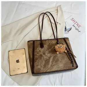 Flat lay of retro brown tote bag with plush charm, tablet and magazine on ivory blazer