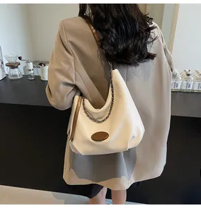 Dettaglio borsa hobo in pelle color crema con tracolla a catena marrone su modella