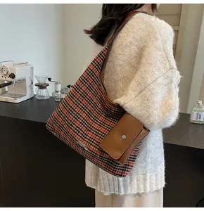 Detail of houndstooth tote bag with leather accessory and metal plate in a cafe