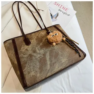 Close-up of vintage distressed denim tote bag with leather trim and plush charm