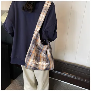 Detail of blue and orange plaid tote bag showing wide strap and Ourface Party logo