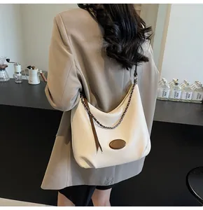 Dettaglio borsa tote bianca in pelle martellata con tracolla a catena indossata