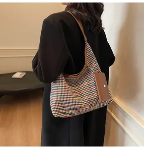 Detail of houndstooth crossbody bag with brown leather trim worn by model on shoulder