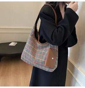 Detail of houndstooth tote bag with brown leather strap and mini pouch charm