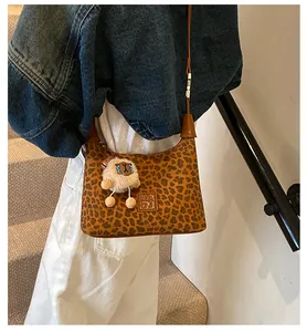 Détail du sac bandoulière léopard avec breloque mouton sur une tenue en denim