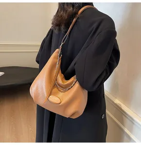 Borsa hobo marrone a grana con catena argento indossata da modella su cappotto nero