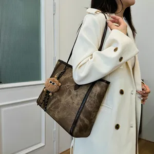 Retro deep brown large capacity tote bag with plush charm on a model in a trench coat