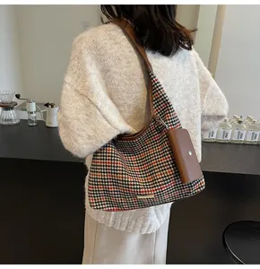 Detailed view of houndstooth tote bag with brown leather straps and small coin purse