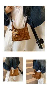 Détail du sac hobo à imprimé léopard avec un charm mouton en peluche sur un escalier