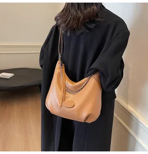 Vista posteriore di una modella con borsa hobo in pelle caramello e catena argento