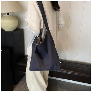 Detail of dark grey tote bag with plaid lining shown on shoulder in cozy interior