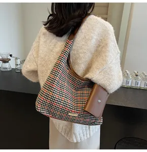 Detail of houndstooth shoulder bag with brown leather trim and detachable pouch accessory