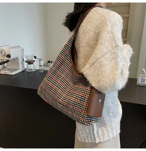 Detail of houndstooth shoulder bag with brown leather strap and small matching pouch