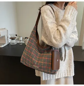 Close-up of houndstooth tote bag with brown leather strap and detachable pouch accessory