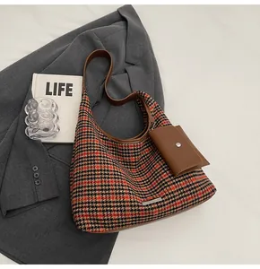 Detail of houndstooth shoulder bag with brown leather strap and mini coin purse charm