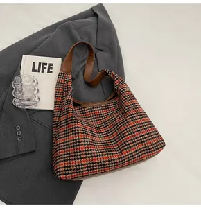 Detail of red and black houndstooth tote bag with brown leather strap and elegant texture