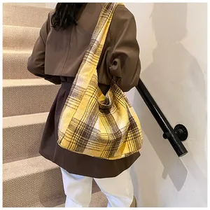 Detail of yellow plaid tote bag styled with deep brown coat on a shoulder strap