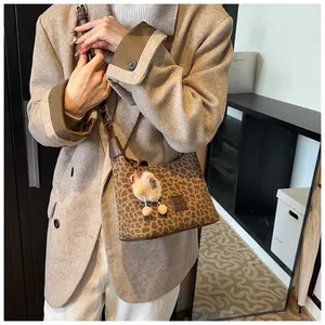 Detail of leopard print shoulder bag with plush charm and embossed leather logo patch
