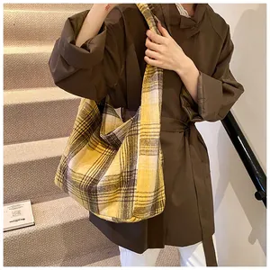 Macro detail of high-capacity yellow plaid wool hobo bag with wide shoulder strap design