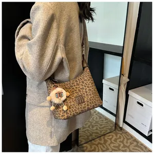 Detail view of leopard print hobo bag with leather logo patch and plush doll charm