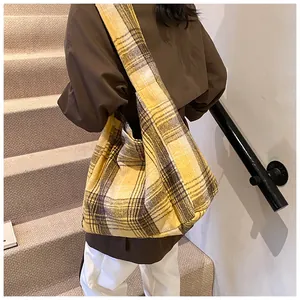 Macro shot of thick yellow plaid wool texture and wide shoulder strap on a tote bag