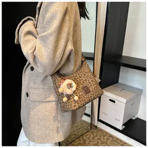 Chic leopard print shoulder bag with a cute sheep plush charm on a beige blazer model