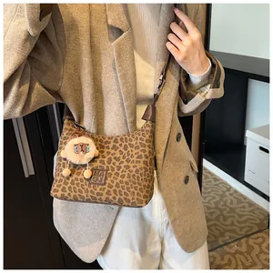 Close-up of leopard print shoulder bag with cute plush sheep charm and brown leather trim