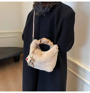Modische beige Plüsch-Beuteltasche mit Ledergriffen und niedlichem Puppenanhänger-Detail